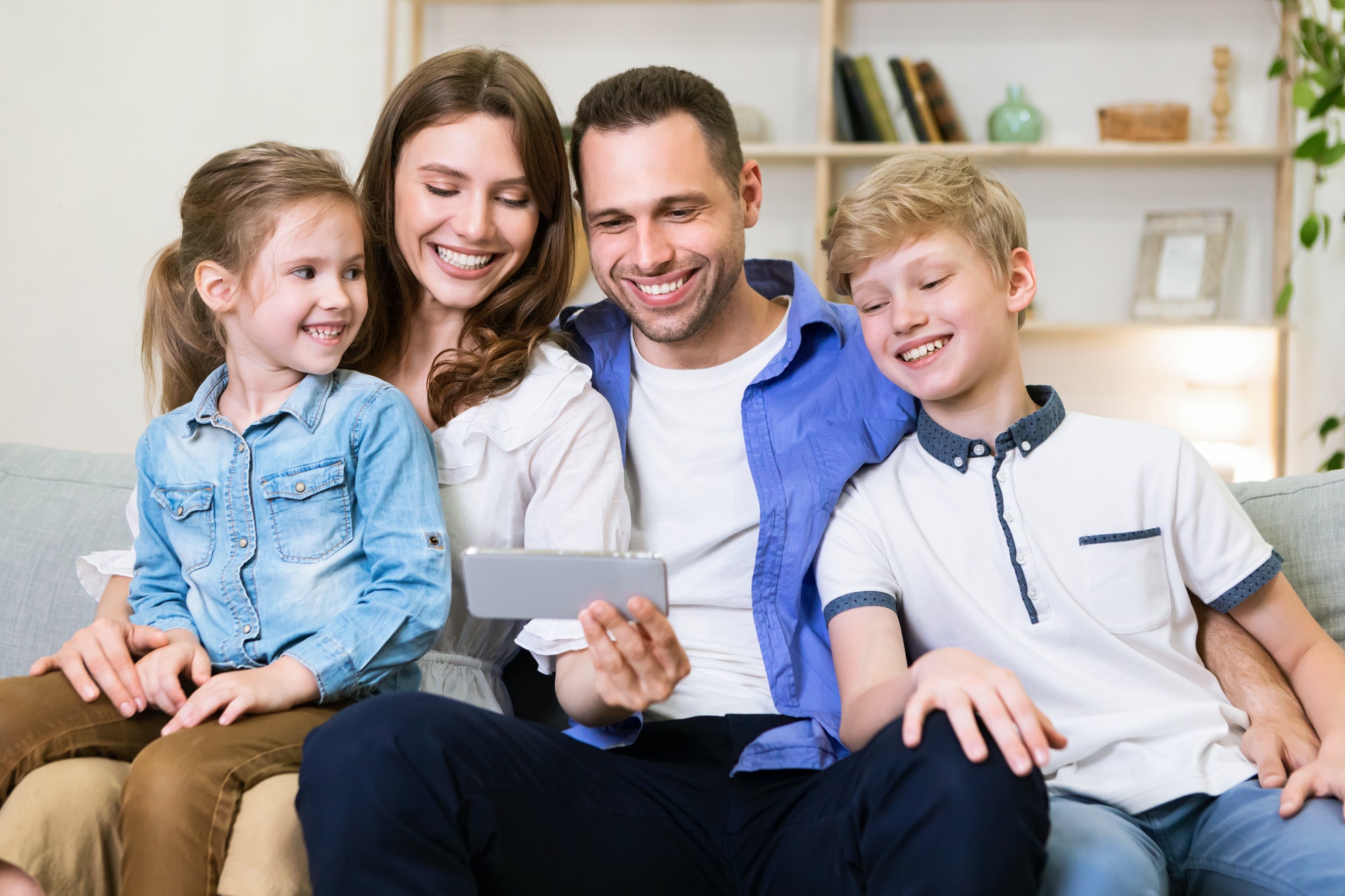 family using smartphone browsing internet together at home on weekend